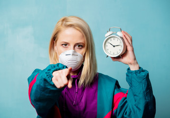 Blonde woman in face mask and 90s style clothes with alarm clock
