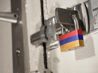 A bolted door secured by a padlock with the national flag of Armenia on it.(series)