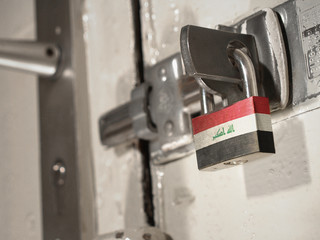 A bolted door secured by a padlock with the national flag of Iraq on it.(series)