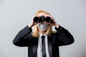 Businesswoman in black suit and face mask with binoculars