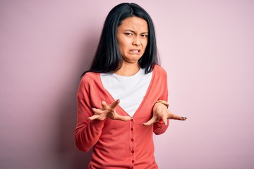 Young beautiful chinese woman wearing casual sweater over isolated pink background disgusted expression, displeased and fearful doing disgust face because aversion reaction.