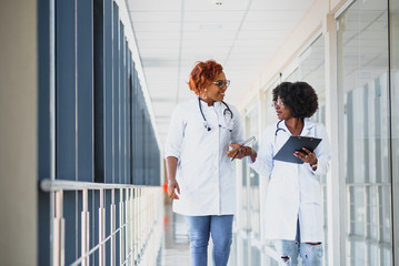 Portrait confident African American female doctor medical professional writing patient notes...