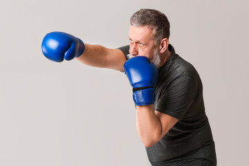 Sporty elderly male boxer on grey background