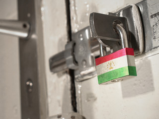 A bolted door secured by a padlock with the national flag of Tajikistan on it.(series)