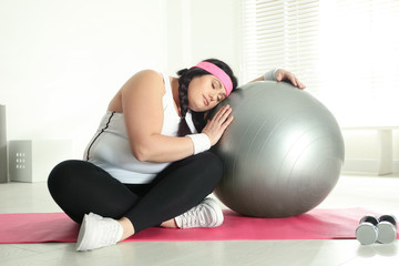 Fototapeta na wymiar Lazy overweight woman leaning fit ball at gym