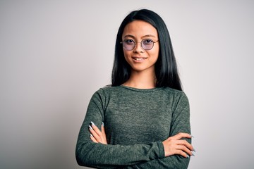 Young beautiful chinese woman wearing glasses and t-shirt over isolated white background happy face smiling with crossed arms looking at the camera. Positive person.