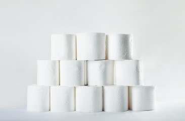 Stacked tower of soft toilet paper rolls on white background. Crisis shortage shop item concept.