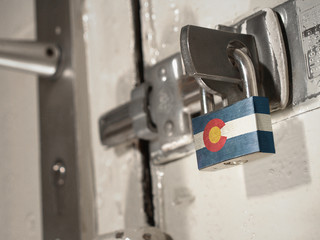 A bolted door secured by a padlock with the national flag of Colorado on it.(series)