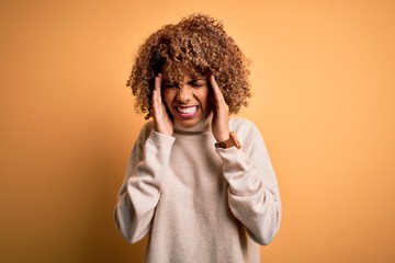 Young beautiful african american woman wearing turtleneck sweater over yellow background with hand on headache because stress. Suffering migraine.