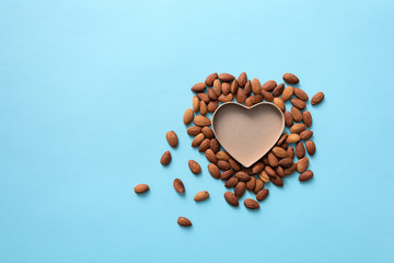 Open and empty heart shaped box with almond around it. Top view background.