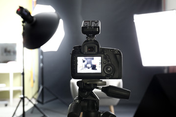 Professional camera on tripod in modern photo studio