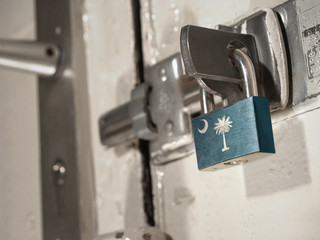 A bolted door secured by a padlock with the national flag of South Carolina on it.(series)