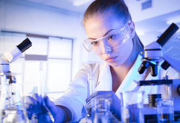 Laboratory interior. Science research concept. Young scientist during experiment and using microscope in modern laboratory.