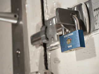 A bolted door secured by a padlock with the national flag of Wisconsin on it.(series)