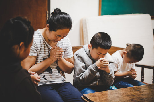 Mother and children praying and praising God at home