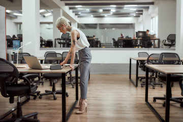 Business professional. Young stylish tattooed business lady working on project while standing near office desk. Business concept