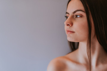 Naklejka premium The face of a beautiful caucasian teenage girl in front of a gray wall