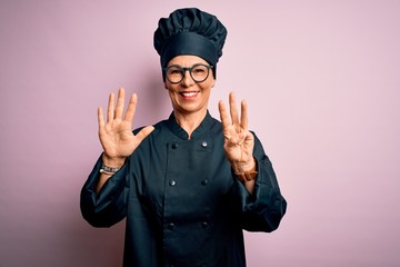 Middle age brunette chef woman wearing cooker uniform and hat over isolated pink background showing and pointing up with fingers number eight while smiling confident and happy.