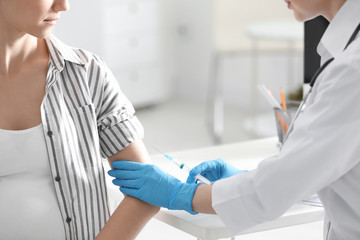 Fototapeta premium Doctor giving injection to pregnant woman in hospital, closeup. Vaccination concept