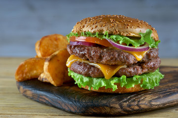 Double cheeseburger with fried potatoes on a light background