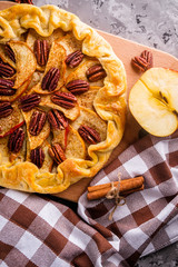 crispy apple galette with pecans on a rustic wooden background