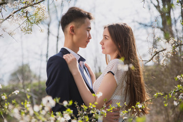 A guy embraces a girl against the background of blooming gardens