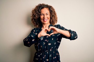 Middle age beautiful woman wearing casual dress standing over isolated white background smiling in love showing heart symbol and shape with hands. Romantic concept.