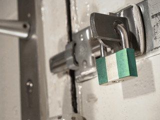 A bolted door secured by a padlock with the national flag of Nigeria on it.(series)