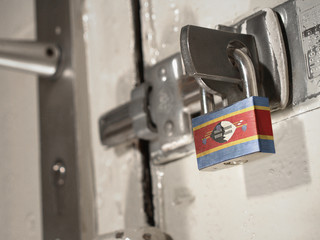 A bolted door secured by a padlock with the national flag of Swaziland on it.(series)