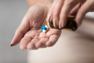Close up older wrinkled female hands taking medicament pills out of bottle. Middle aged woman preparing take nutrition supplements, vitamins, antibiotics, emergency medicine. Healthcare concept.