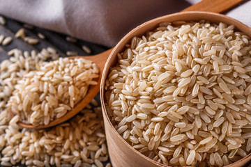raw brown rice on dark rustic wooden background