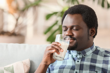 Fototapeta na wymiar Young African-American man drinking milk at home