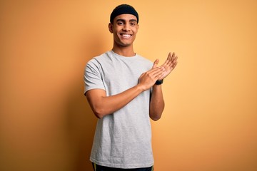 Handsome african american sportsman doing sport wearing sportswear over yellow background clapping and applauding happy and joyful, smiling proud hands together