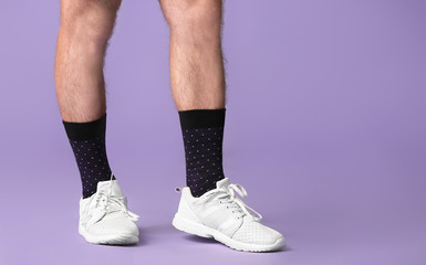 Male legs in socks and shoes on color background