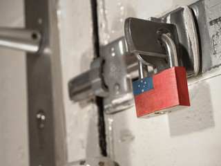 A bolted door secured by a padlock with the national flag of Samoa on it.(series)