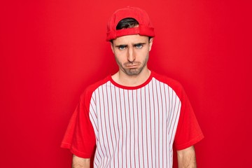 Young handsome sporty man with blue eyes wearing striped baseball t-shirt and cap skeptic and nervous, frowning upset because of problem. Negative person.