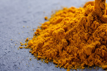 natural turmeric powder on a dark stone background