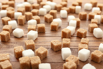 Fototapeta na wymiar Cubes of sweet sugar on wooden background