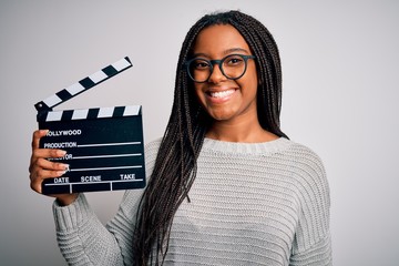 Young african american director girl filming a movie using clapboard over isolated background with...