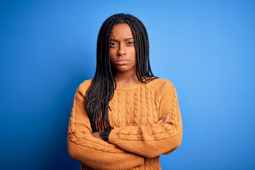 Young african american woman wearing casual yellow sweater standing over blue isolated background...