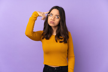 Young mixed race woman isolated on purple background making the gesture of madness putting finger on the head