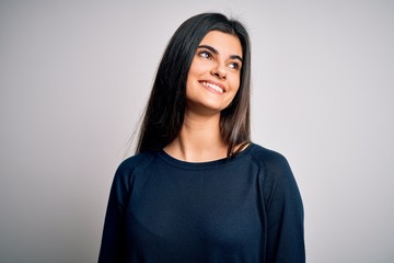 Obraz premium Young beautiful brunette woman wearing casual sweater standing over white background looking away to side with smile on face, natural expression. Laughing confident.