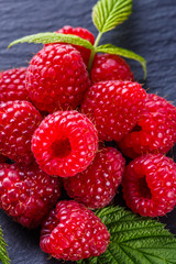 juicy fresh natural raspberries on a dark stone background