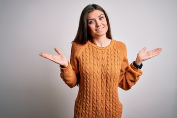 Young beautiful woman with blue eyes wearing casual sweater standing over white background clueless...