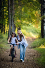 Mother taking his child for bycicle ride. Help with a first ride on a bike.