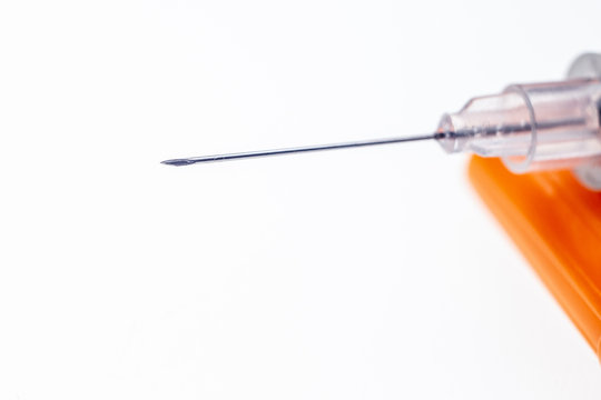 Insulin syringe needle with a drop on a white background.