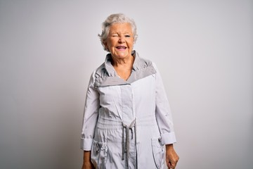 Senior beautiful grey-haired woman wearing casual jacket standing over white background winking...