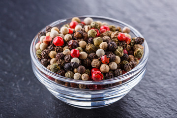 mix of peppercorns on a dark stone background