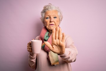 Senior beautiful grey-haired woman drinking mug of coffee over isolated pink background with open hand doing stop sign with serious and confident expression, defense gesture