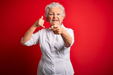 Senior beautiful woman wearing elegant shirt standing over isolated red background smiling doing...